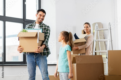 mortgage, family and real estate concept - happy mother, father and little daughter with stuff in boxes moving to new home © Syda Productions