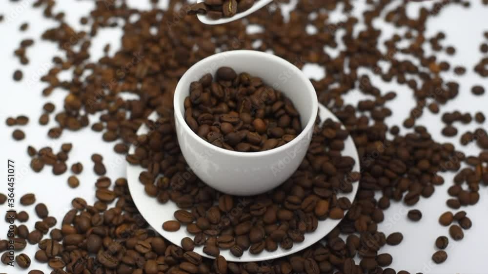 coffee beans fall in white coffee cup on a white background, the concept of cheerfulness coffee beans fall in white coffee cup on a white background, the concept of cheerfulness