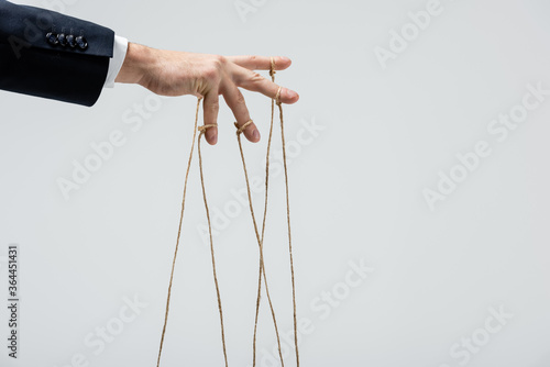 Fotografía partial view of puppeteer with strings on fingers isolated on grey