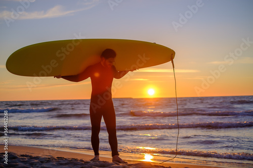 Positive surfer carrying surfboard during sunset