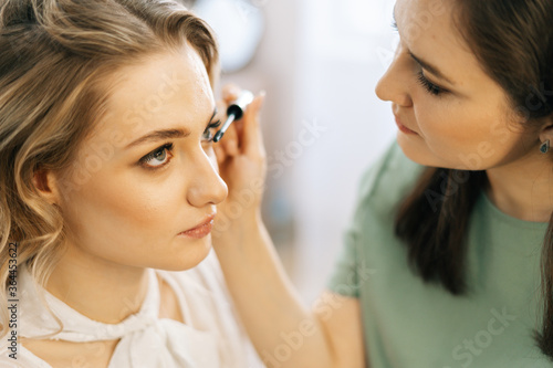 Close-up of professional make-up artist putting shadows on eyelids in beauty salon. Concept of beauty  fashion and stylish makeup.