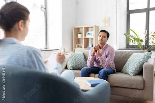 psychology, mental therapy and people concept - young indian man patient and woman psychologist at psychotherapy session