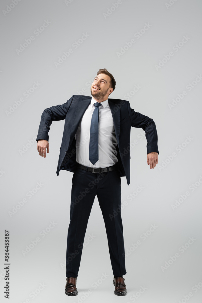 happy businessman marionette in suit posing with hands down isolated on grey happy businessman marionette in suit posing with hands down isolated on grey