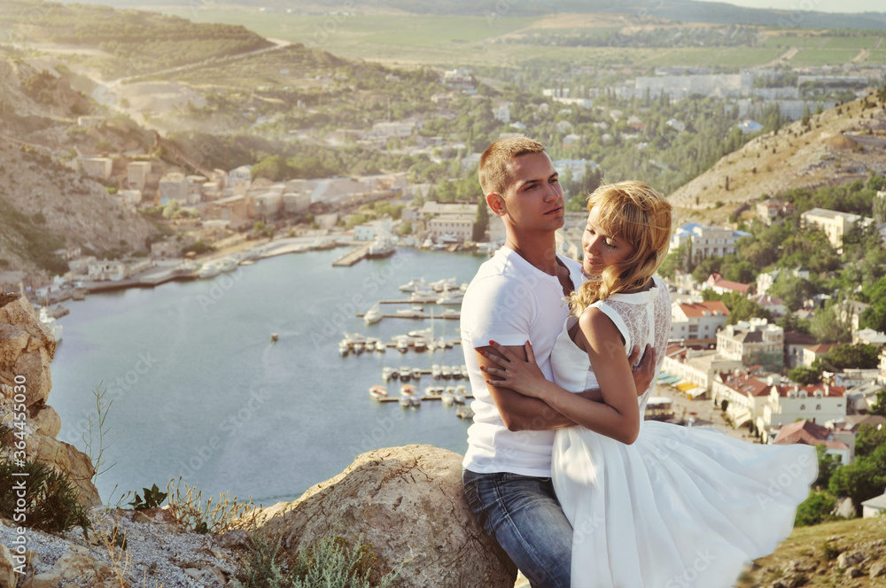 Stunning sensual outdoor portrait of young stylish fashion couple kissing in summer. Soft sunny colors.