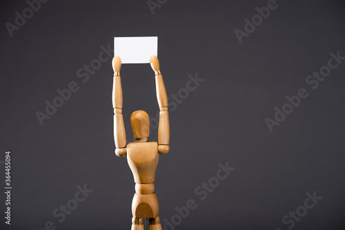 wooden marionette holding blank placard on black background photo