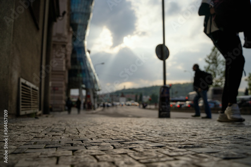 Prague street with dancing house blurred in the background with people walking.