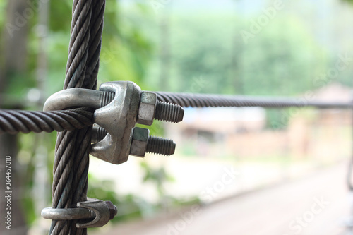 Close up wire rope clips on the bridge with green blur background.