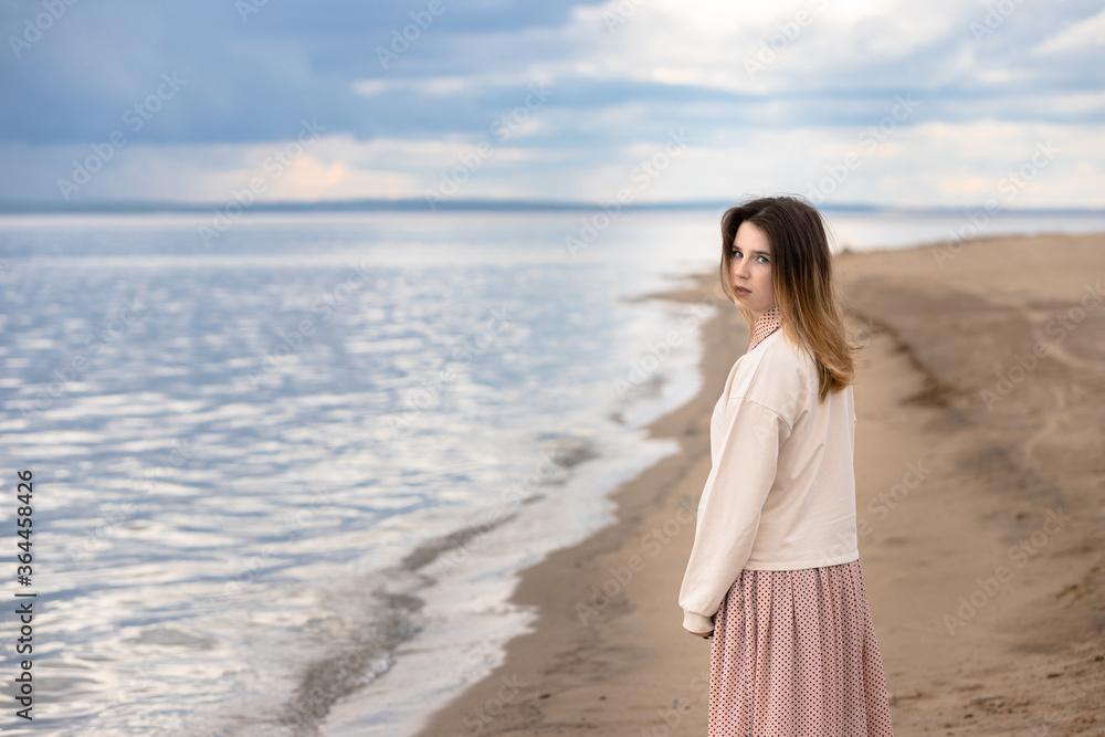 A young beautiful girl walks along the shore and looks back. A young beautiful girl walks along the shore and looks back.