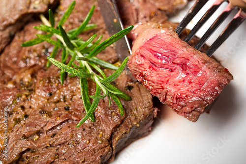 Medium rear beef steak. White plate with Piece of beef steak on fork.
