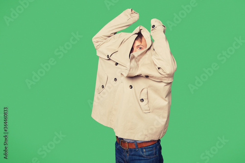 Φωτογραφία Young man wearing jacket while looking from jacket over green background