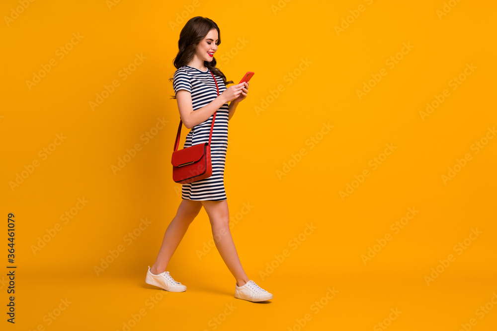 Full body photo of pretty good satisfied lady teenager walking using telephone isolated bright color yellow background Full body photo of pretty good satisfied lady teenager walking using telephone isolated bright color yellow background