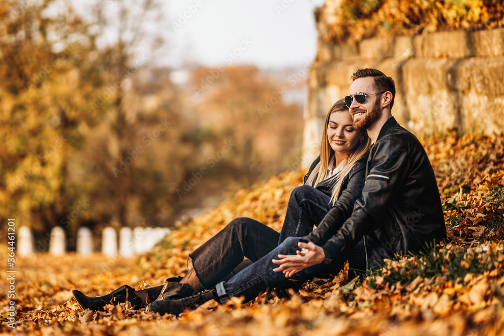 Portrait of a young loving couple, sitting in autumn leaf and enjoying nature. Portrait of a young loving couple, sitting in autumn leaf and enjoying nature.