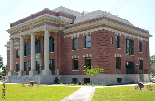 A fine example of a neo-classical, red brick and concrete building, constructed and used as the county courthouse. There are neat lawns and pedestrian access in the foreground. © mike