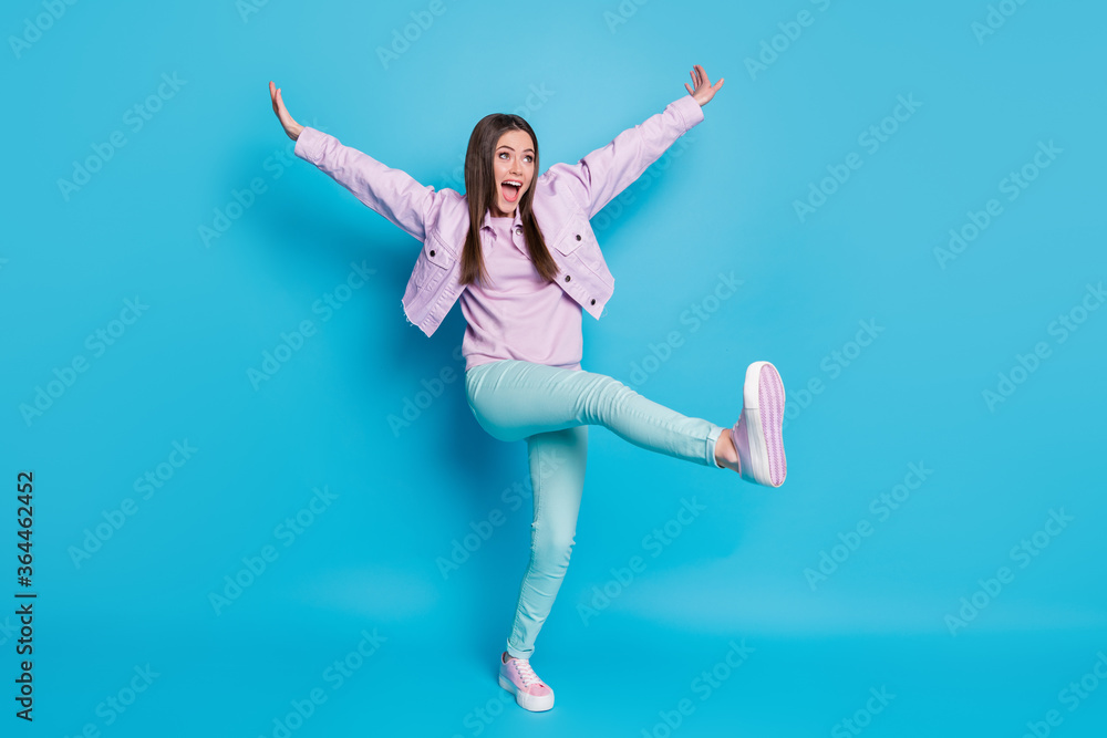 Full length photo of crazy funny lady raise hands leg high up dancing students party good mood rejoicing wear casual denim violet jacket pullover pants shoes isolated blue color background