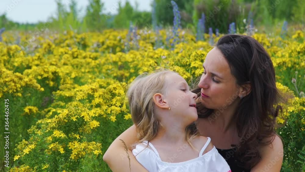 Happy Young Mother and her Cute Little Daughter Hugging in a Blooming Summer Field. Slow Motion. Mothers Day Holiday, Happy Childhood and Summer Vacation Concept Happy Young Mother and her Cute Little Daughter Hugging in a Blooming Summer Field. Slow Motion. Mothers Day Holiday, Happy Childhood and Summer Vacation Concept