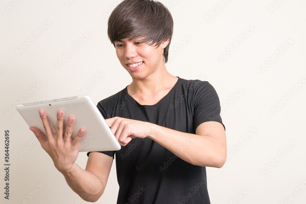 Portrait of happy young Filipino man using digital tablet Portrait of happy young Filipino man using digital tablet