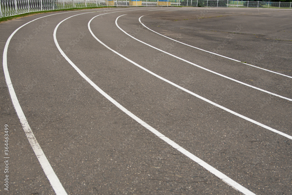 white markings for running in a sports stadium. outdated asphalt pavement at the stadium.