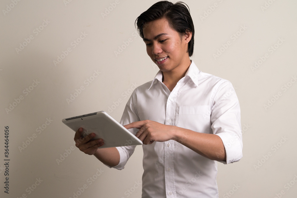 Portrait of happy young Filipino businessman using digital tablet Portrait of happy young Filipino businessman using digital tablet