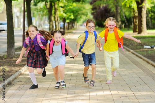 Billede på lærred small schoolchildren with colorful school bags and backpacks run to school