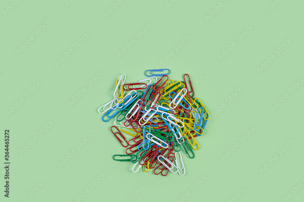 Bunch of colorful paper clips on green background. Creative flat lay back to school concept with paper clips. Top view copy space