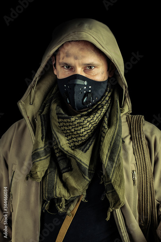 man with burglar crowbar wearing black protactive face mask and jacket with hood on black background photo