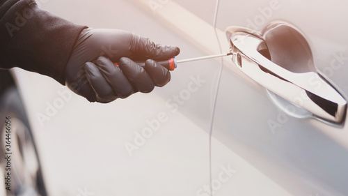 Obraz na plátne Close up car thief hand holding screwdriver tamper yank and glove black stealing automobile trying door handle to see if vehicle is unlocked  trying to break into inside