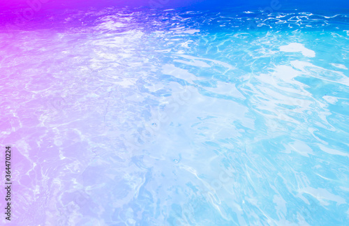 Surface of blue swimming pool toned in multicolored neon. Background of blue ripped water in swimming pool. Neon background