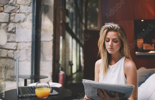 Εκτύπωση καμβά Beautiful Sweden woman reading newspaper while resting after work on laptop comp