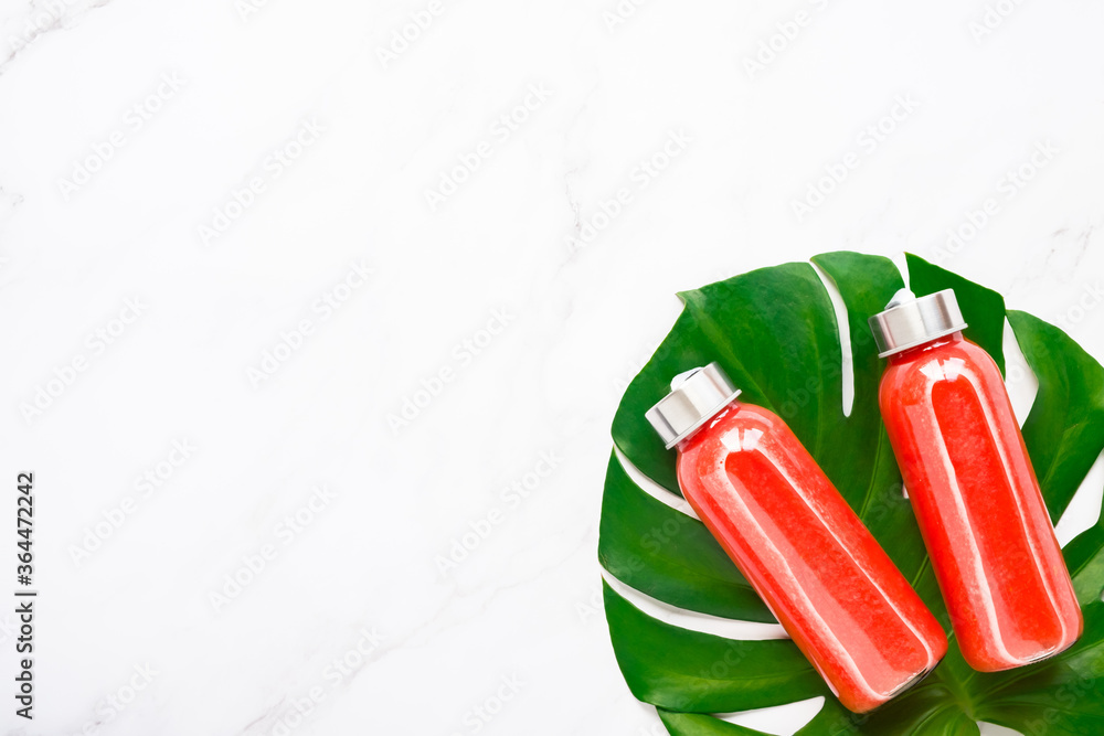 Fitness, healthy nutrition diet concept. Fresh cool watermelon juice in a glass jar and tropical monstera leaf on a light background. Summer concept. copy space top view flat lay