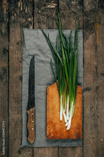 Green onions on an old wooden background. The view from the top. Art.