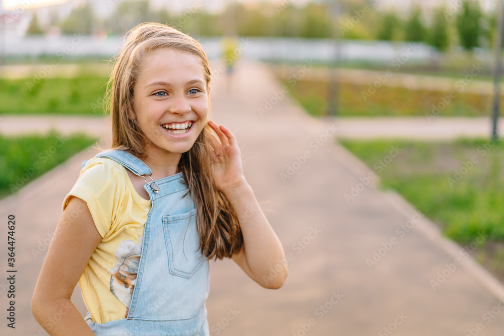 Portrait of a laughing little girl child 9-12 years old in a denim jumpsuit on the street on a Sunny day Portrait of a laughing little girl child 9-12 years old in a denim jumpsuit on the street on a Sunny day