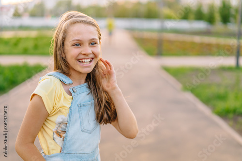 Canvas Print Portrait of a laughing little girl child 9-12 years old in a denim jumpsuit on t
