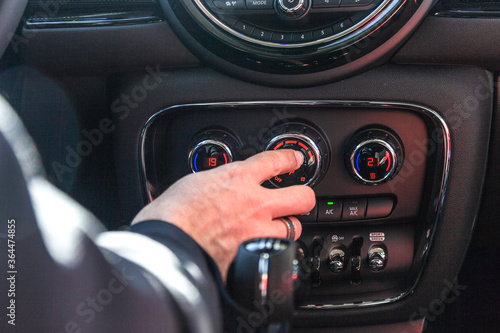 Una mano manipula los botones de un salpicadero para gestionar el aire acondicionado del coche