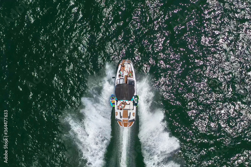 Speed boat with people roaring across the Sea at high speed, Aerial view.