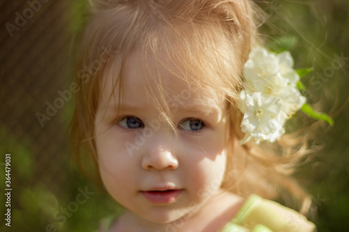 Portrait of a little cute girl with a jasmine flower in her hair