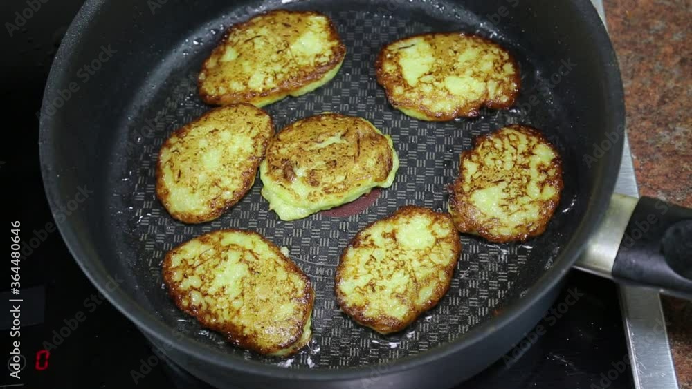 Frying zucchini pancakes in a round pan on an electric stove, cooking baking useful food. Frying zucchini pancakes in a round pan on an electric stove, cooking baking useful food.