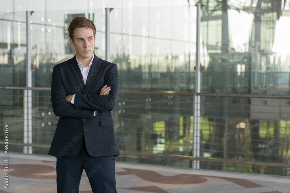 Portrait of young handsome businessman thinking with arms crossed at the airport Portrait of young handsome businessman thinking with arms crossed at the airport