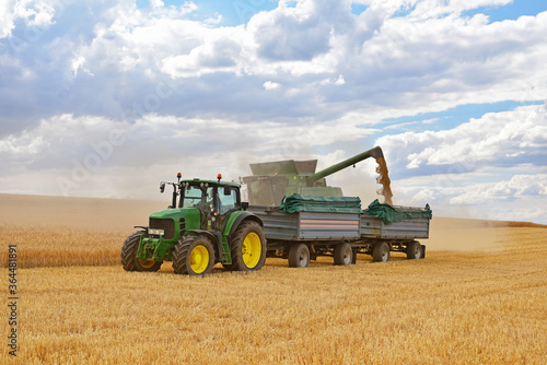 combine harvester and tractor in the cereal field during the summer harvest