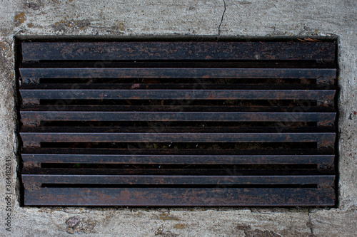Black metal door grill with rust on a concrete floor