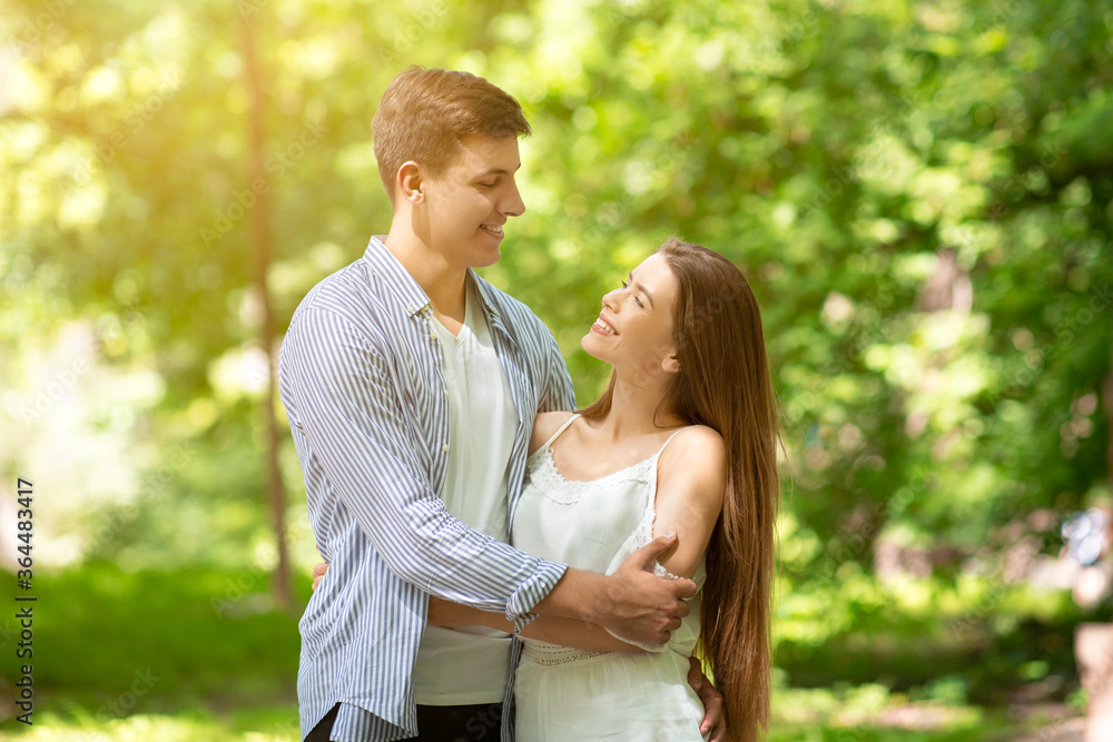 Fototapeta premium Attractive loving couple hugging and looking at each other in summer park