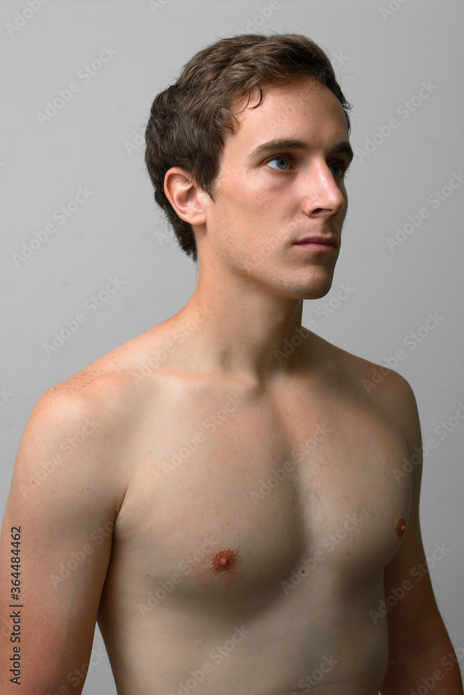 Portrait of young handsome man thinking and looking up shirtless