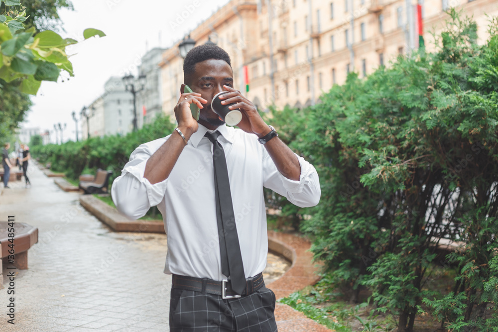 African american businessman in a rush. Man with takeaway coffee talking on the phone in a hurry African american businessman in a rush. Man with takeaway coffee talking on the phone in a hurry