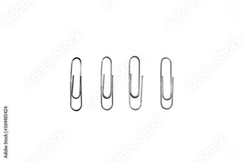 Four silver paper clips isolated on white studio background. Paper clip background / texture
