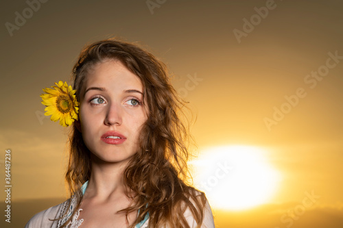 Beautiful young girl posing in a sunflower field at sunset