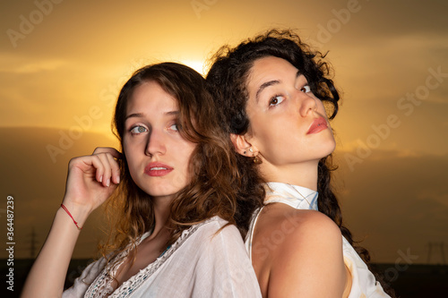 Beautiful young girls posing together at sunset in a sunflower field