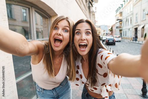 Wallpaper Mural Image of excited adult two women hugging and taking selfie photo Torontodigital.ca