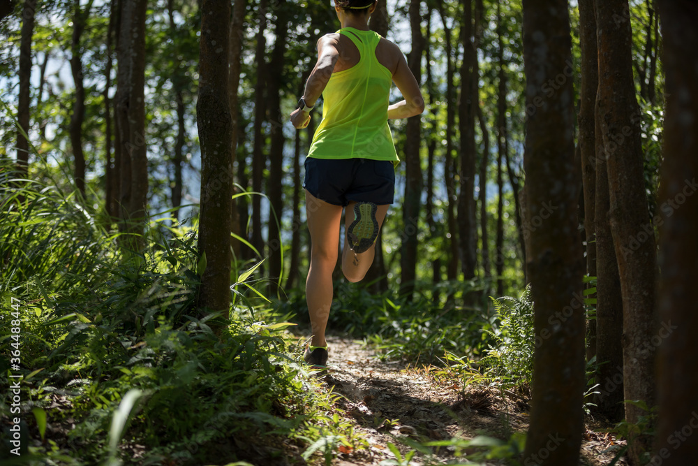 Young woman trail runner running in sunrise tropical forest Young woman trail runner running in sunrise tropical forest