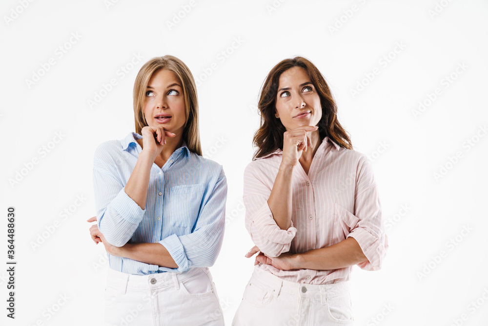 Image of thinking two women looking upward while posing at camera Image of thinking two women looking upward while posing at camera