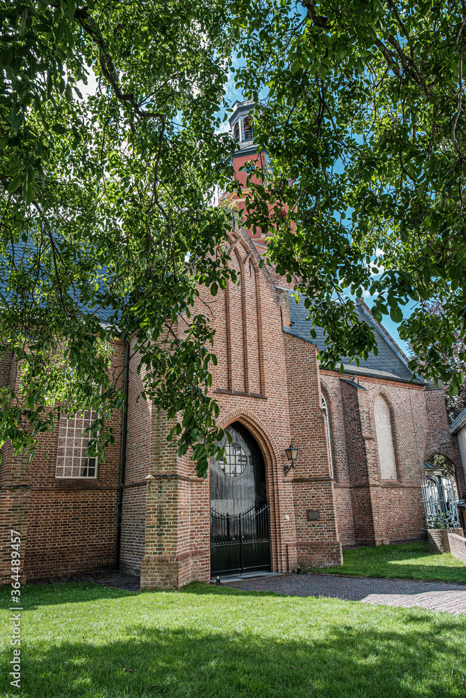 Naklejka premium View of Sint Lambertuskerk protestant church in small town Buren, Gelderland, the Netherlands. Sunny summer day with blue sky with clouds. July 2020
