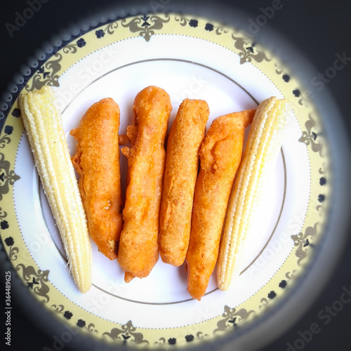 Delicious hot Baby corn baji with fresh baby corn placed in plate with black backgrounds and packed with vital antioxidants and has essential fibres photo